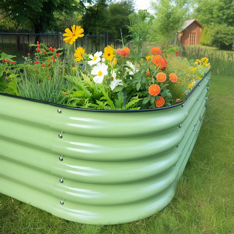 Salbeigrünes Metall Hochbeet, bepflanzt mit bunten Blumen. Das Hochbeet steht auf einer grünen Wiese mit Gartenhaus.