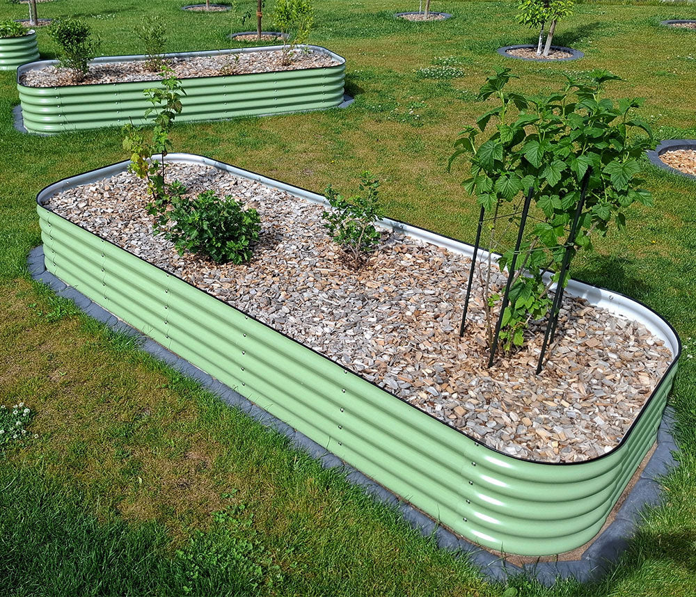 Verlängerte Hochbeete in Salbeigrün mit Beerenbepflanzung und Mulch aus Holzhäckseln.